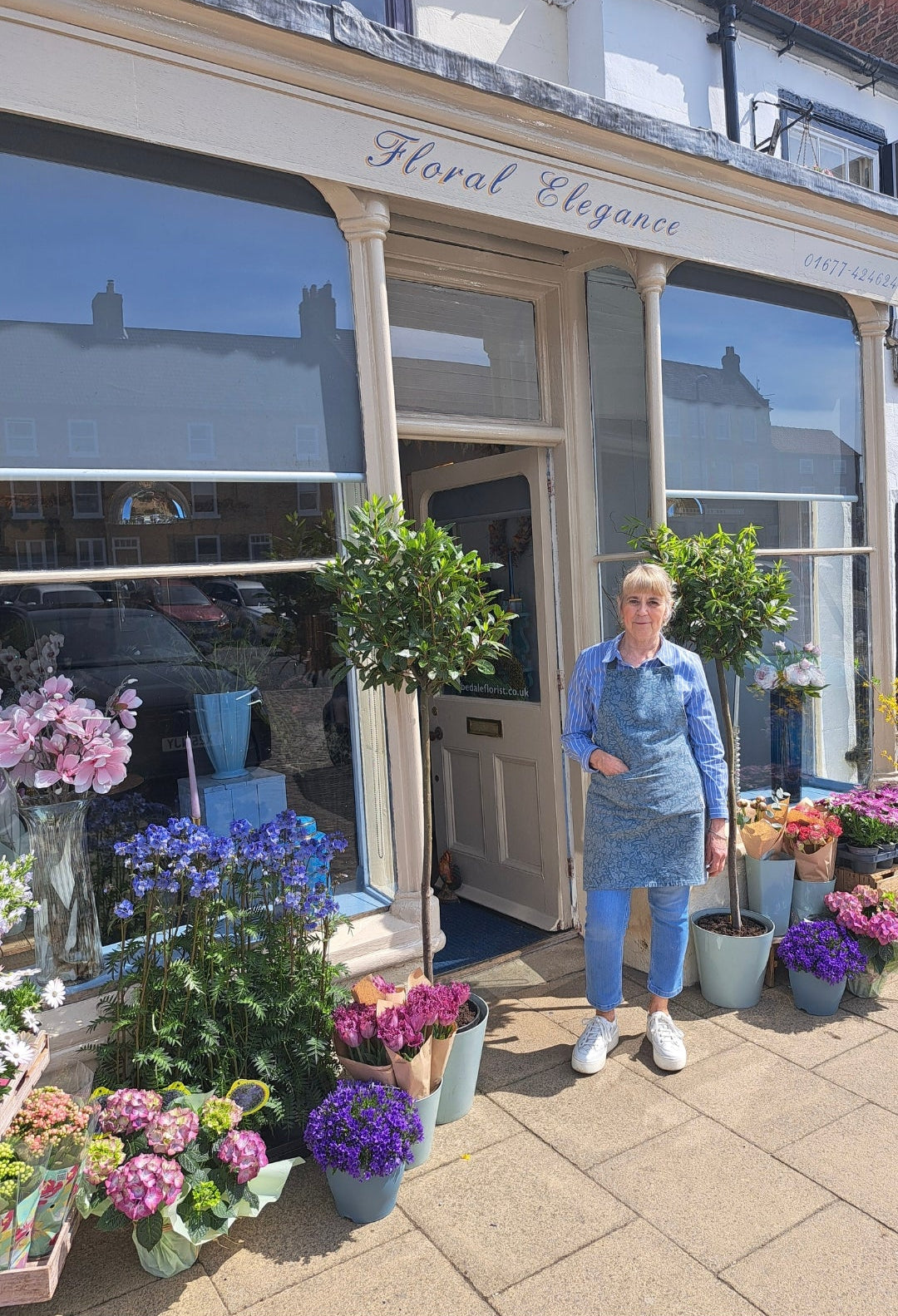 Woman standing outside a floral shop with flowers displayed in front
